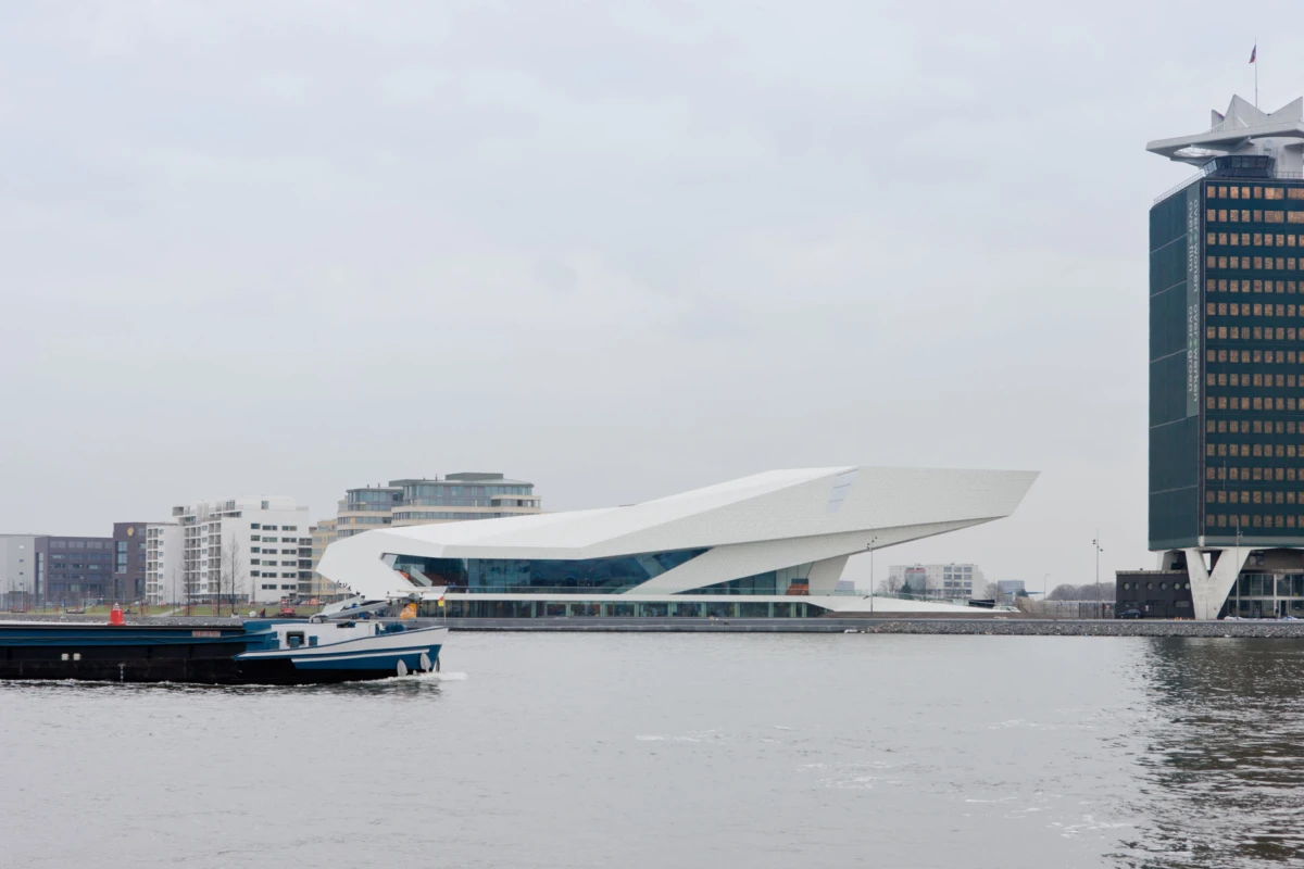 Futuristic white museum along a riverfront with blue-glass facade in a city harbor.