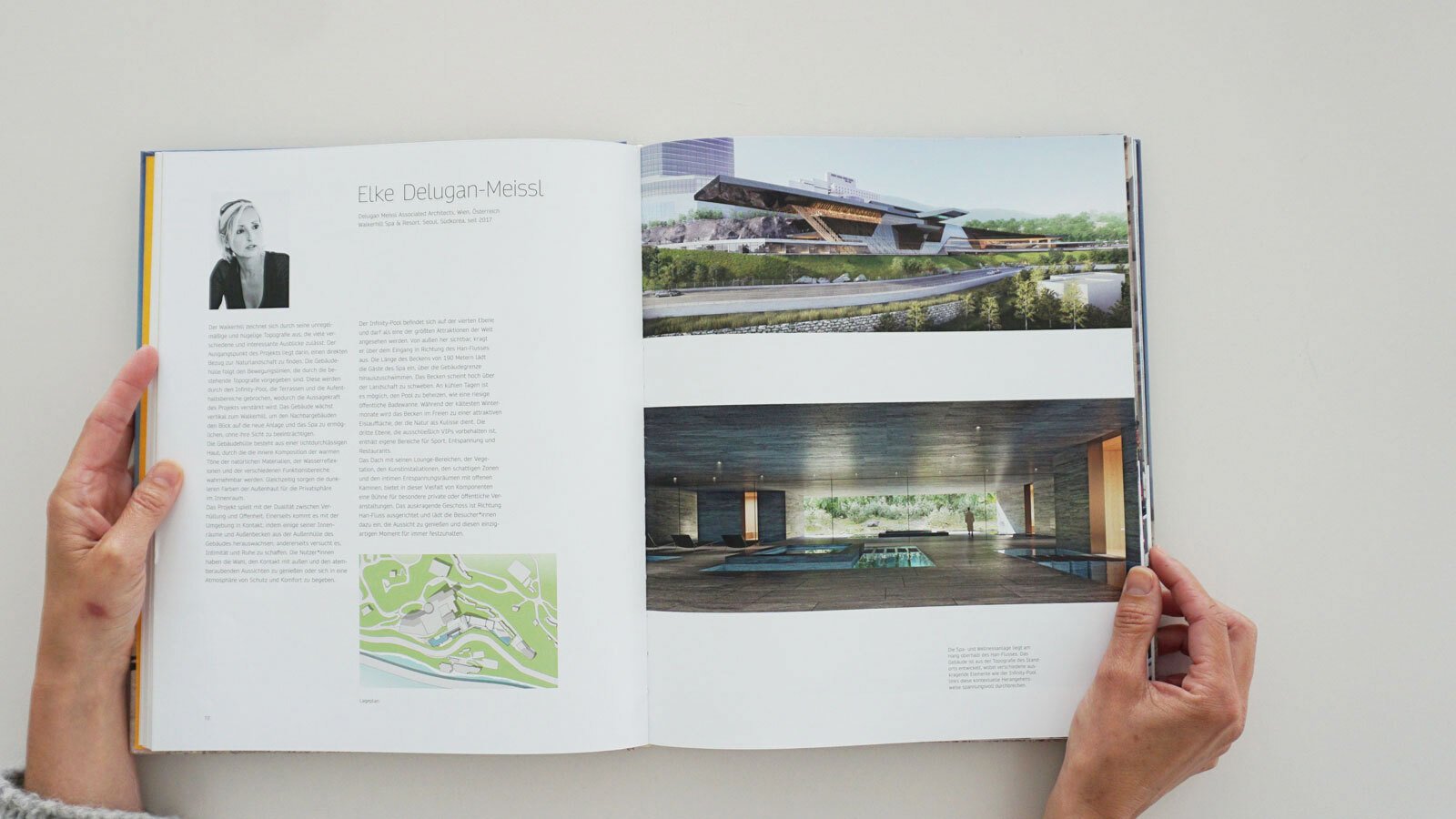 Hands hold open architecture magazine; left page shows a profile photo and text, right page features a modern building exterior and indoor pool.