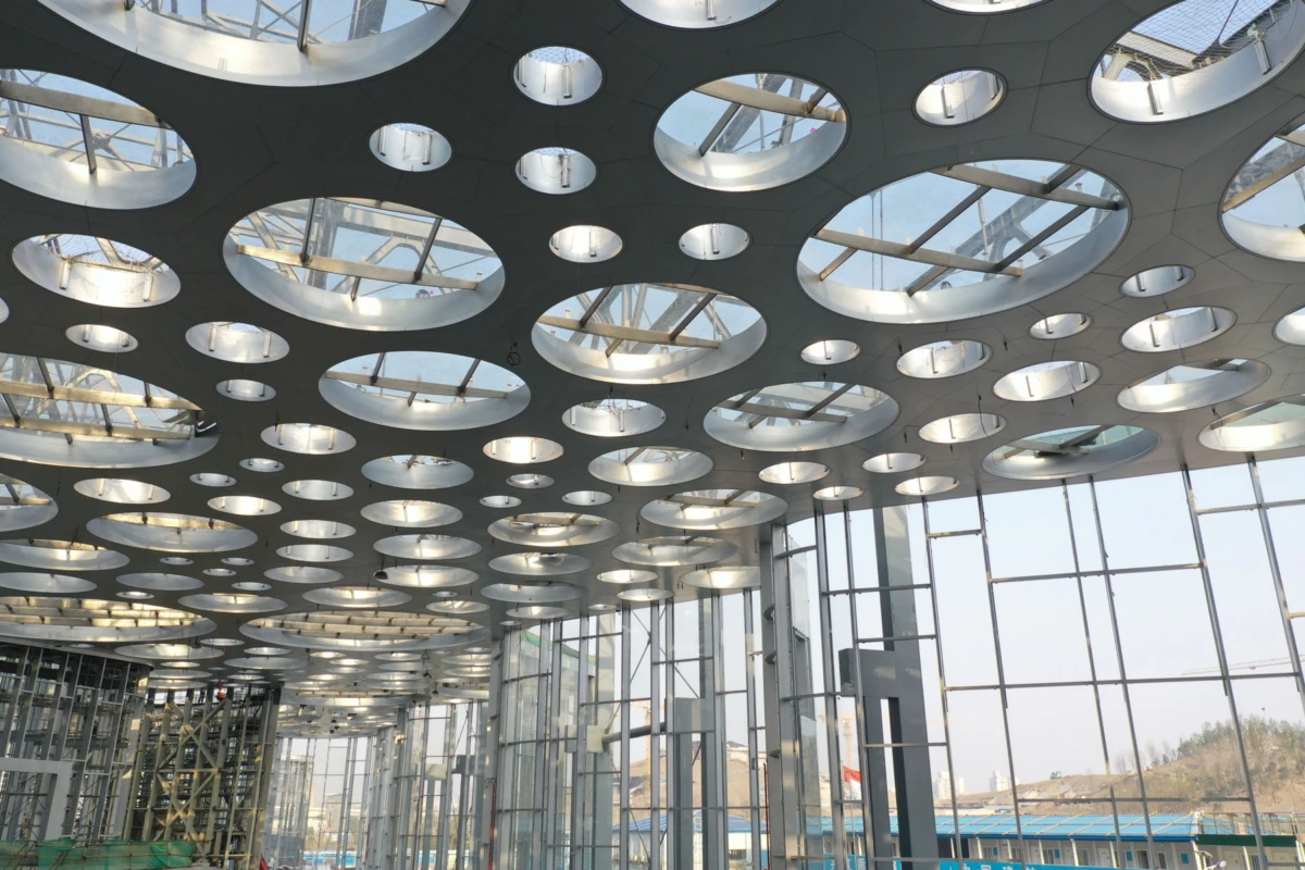 Interior of a modern building under construction, circular skylights in the ceiling and glass walls.