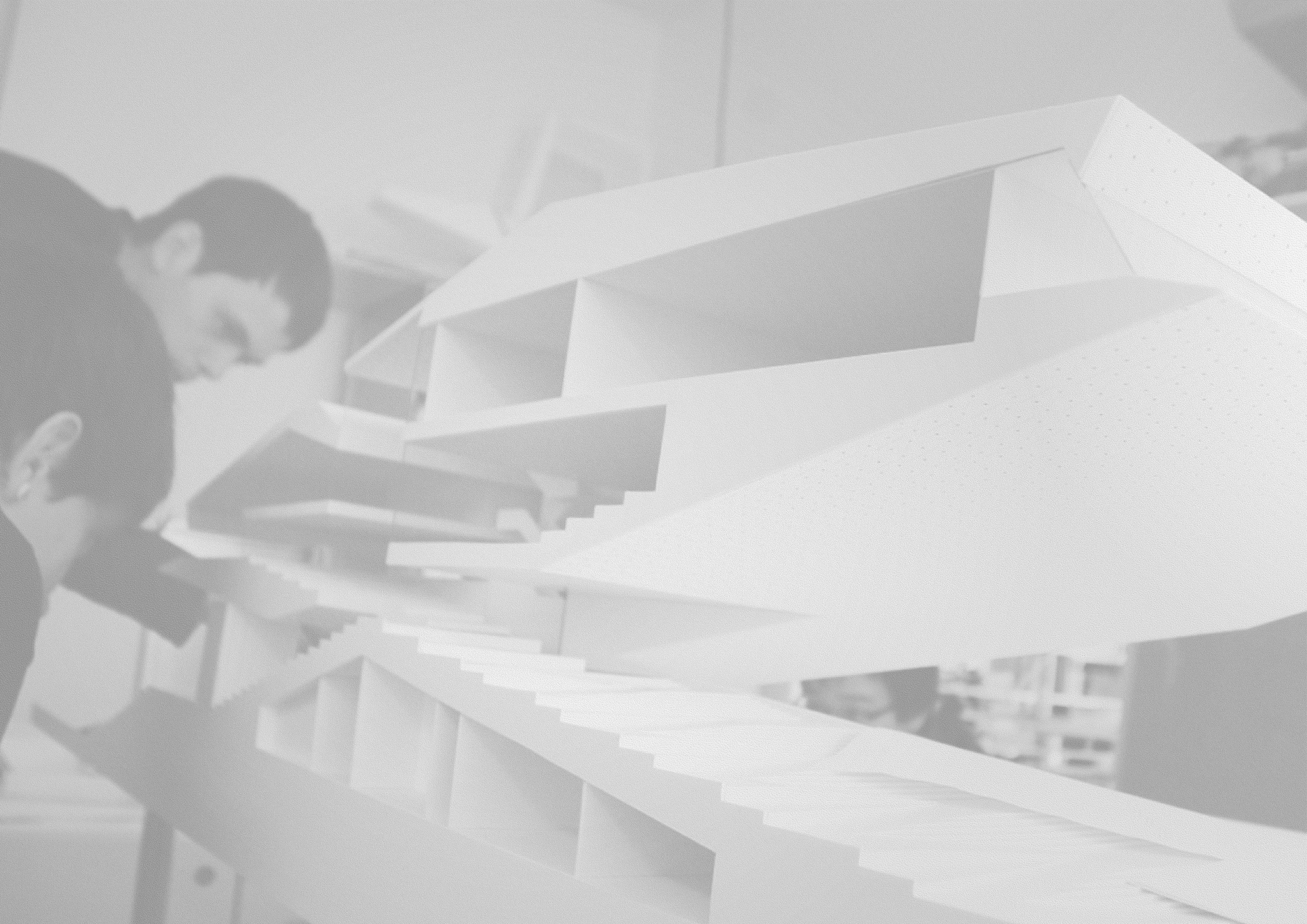 White abstract geometric sculpture with layered stair-like ramps; two people examine it in a design studio.