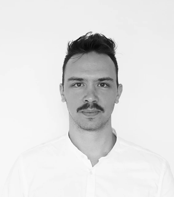 Front-facing portrait of a person with mustache wearing a white shirt against a plain white background.