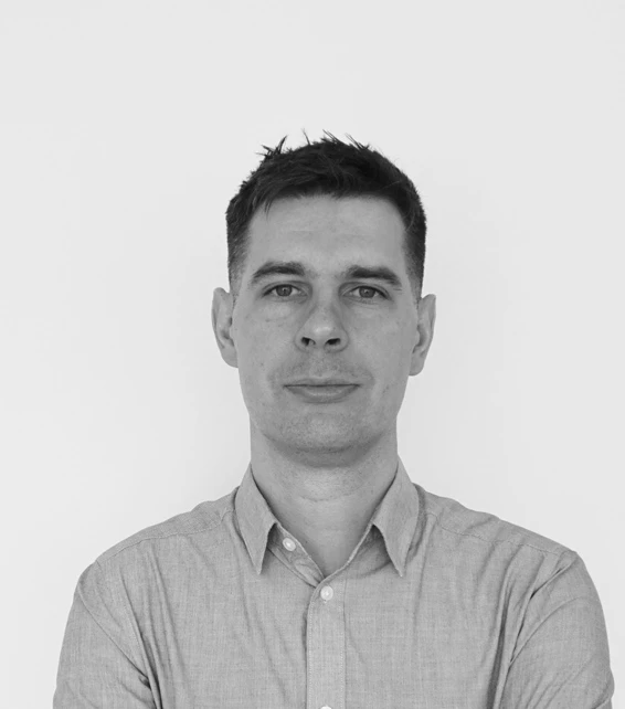 Portrait of an adult person wearing a light button-down shirt, facing the camera against a plain white background.