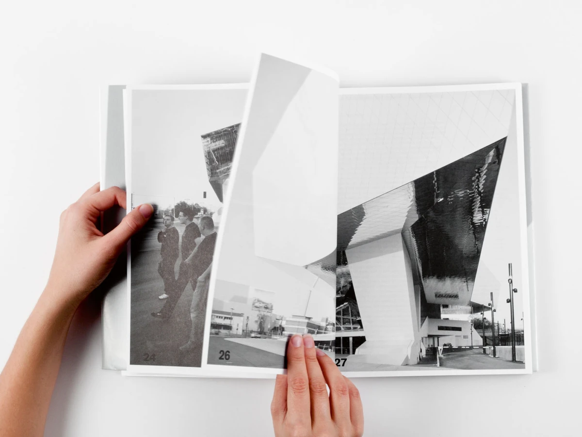 Pair of hands flipping through a black-and-white photo book featuring modern architecture.