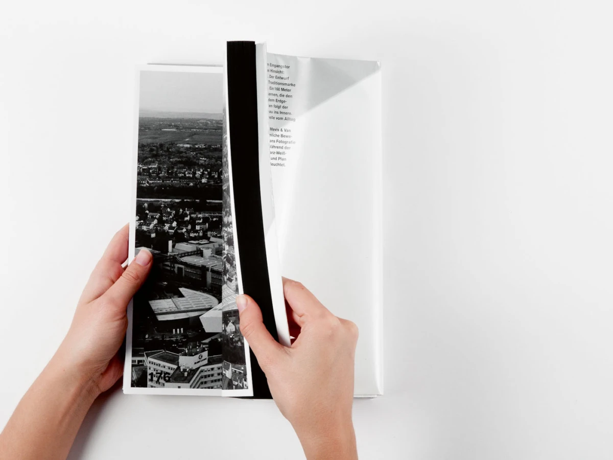 Two hands turning a page in a magazine featuring a black-and-white cityscape photo.