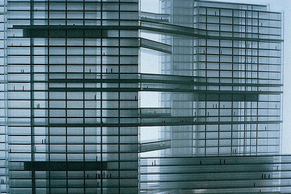Glass-clad office building facade with overlapping horizontal louvers in an urban setting