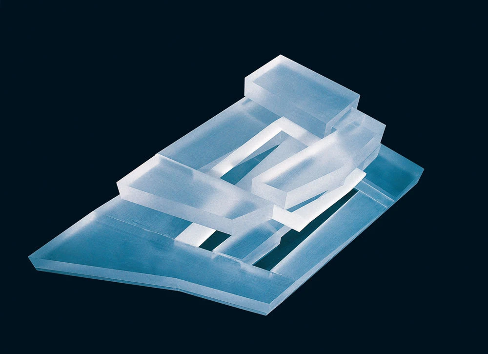 Transparent blue acrylic geometric sculpture with nested rectangular frames stacked on a trapezoidal base against a dark blue background.