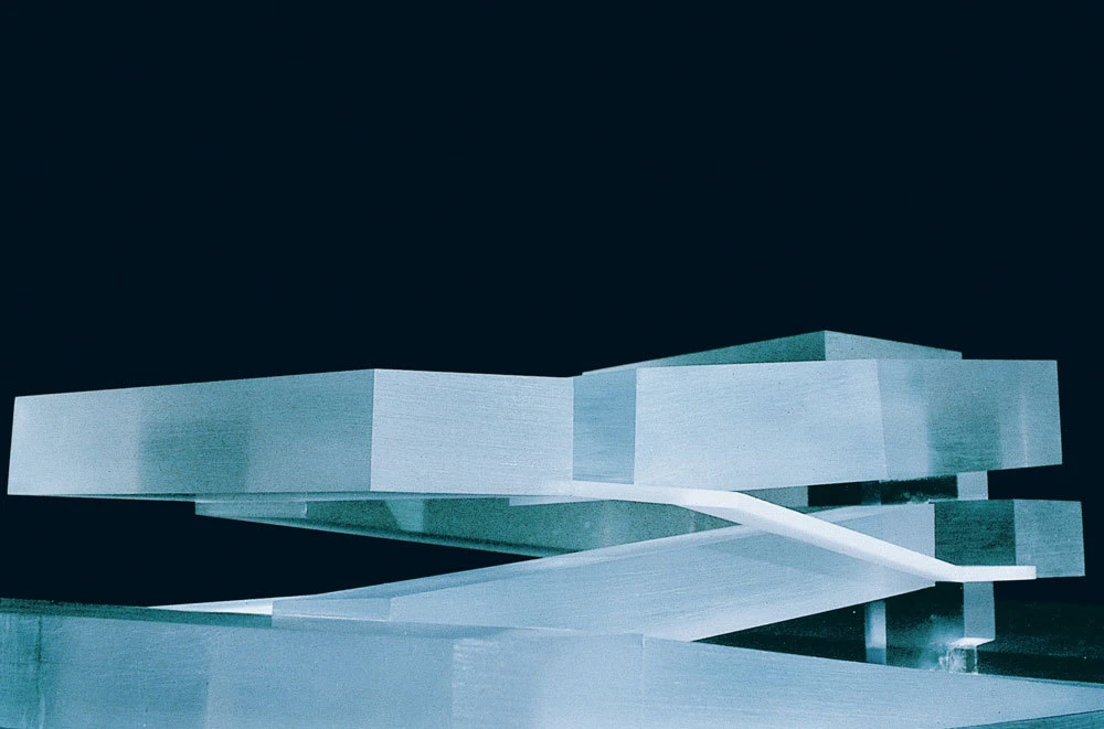 Abstract outdoor sculpture of light-blue rectangular prisms interlocked with a curved white beam against a dark night sky.