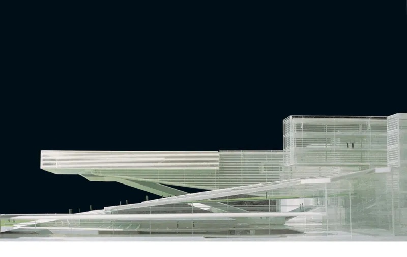 Futuristic glass-and-steel building with elevated walkways and diagonal supports against a dark night sky