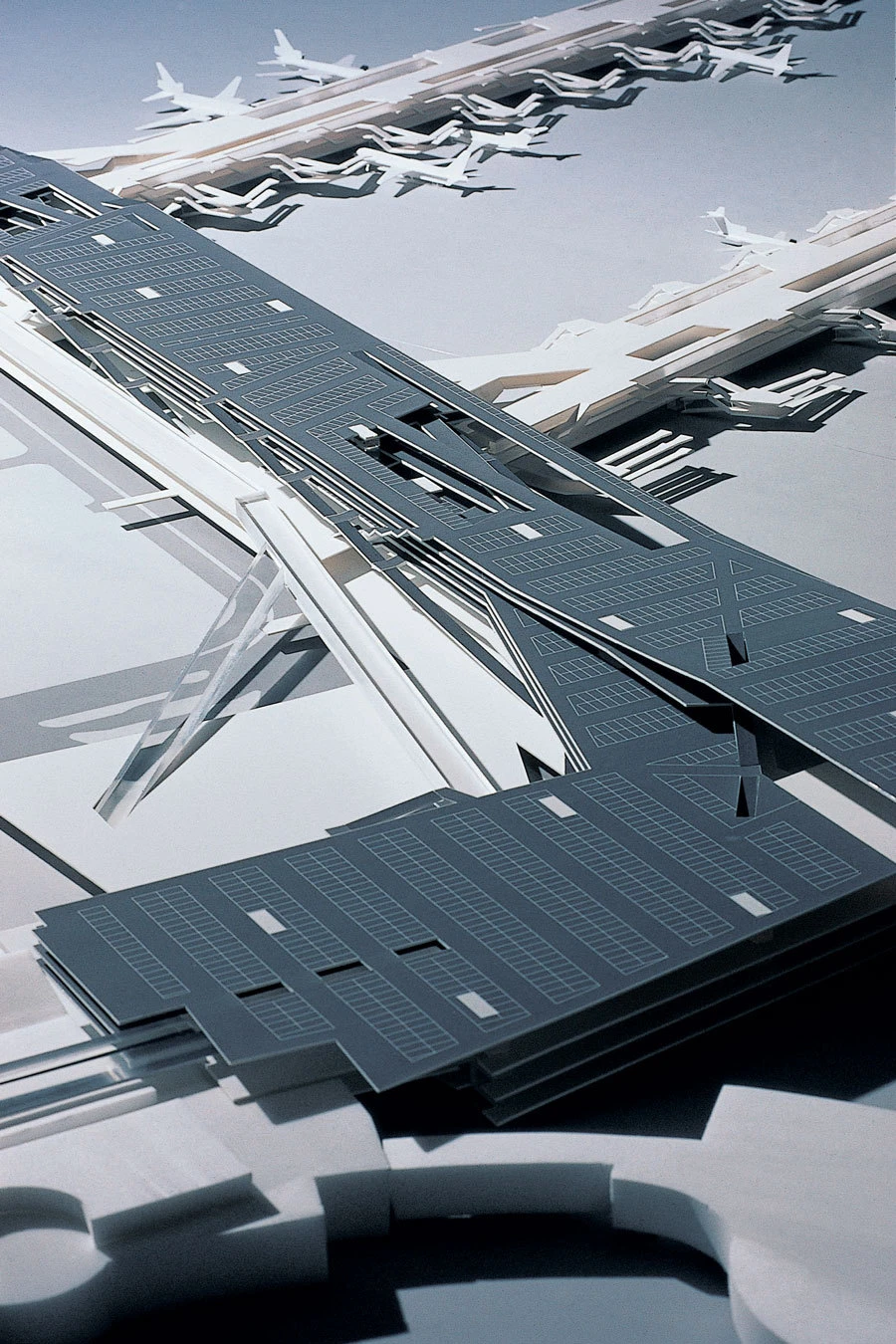 Array of dark blue rectangular panels with grid lines laid diagonally across a white abstract architectural framework.