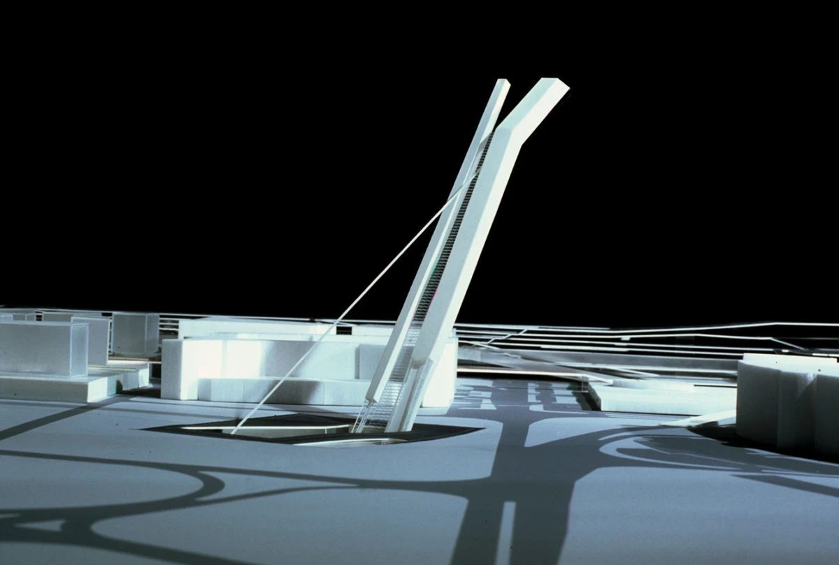 Abstract white architectural sculpture: a tall angled rectangular panel supported by cables on a white rooftop platform against a black background.