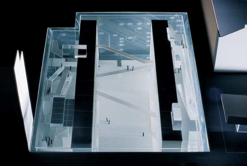 A transparent acrylic architectural model showing staircases, ramps, and platforms inside a glass display case.