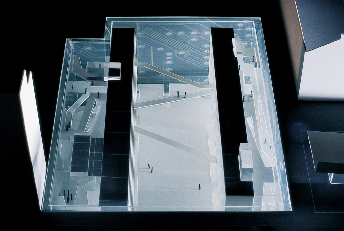 A transparent acrylic architectural model showing staircases, ramps, and platforms inside a glass display case.