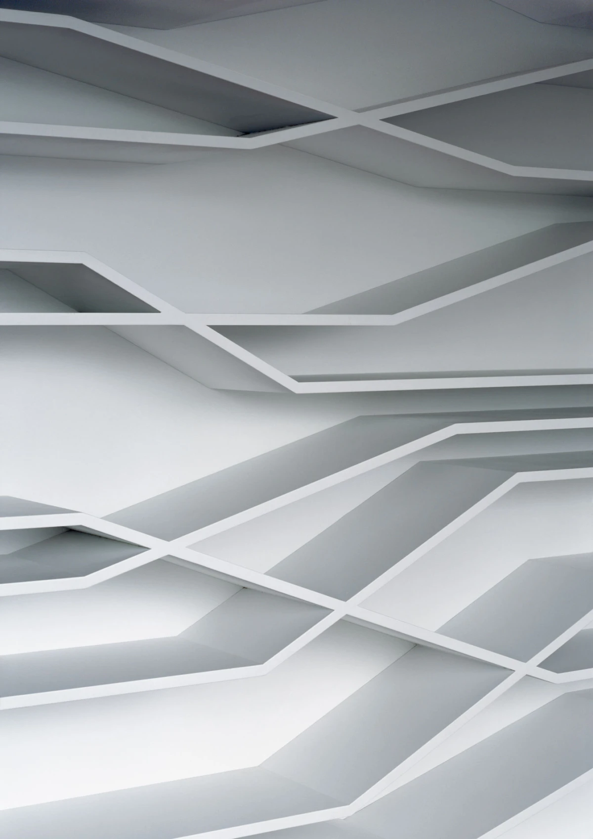 Geometric white ceiling with intersecting angular beams forming diamond-like patterns in an architectural interior.
