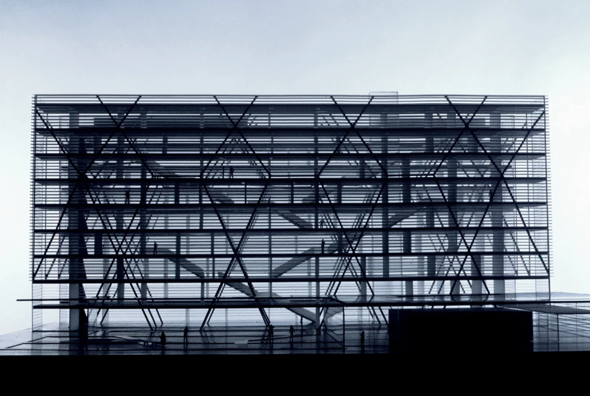 Modern glass-fronted building with crisscross steel framework; interior stairs visible and silhouettes of people on multiple floors.