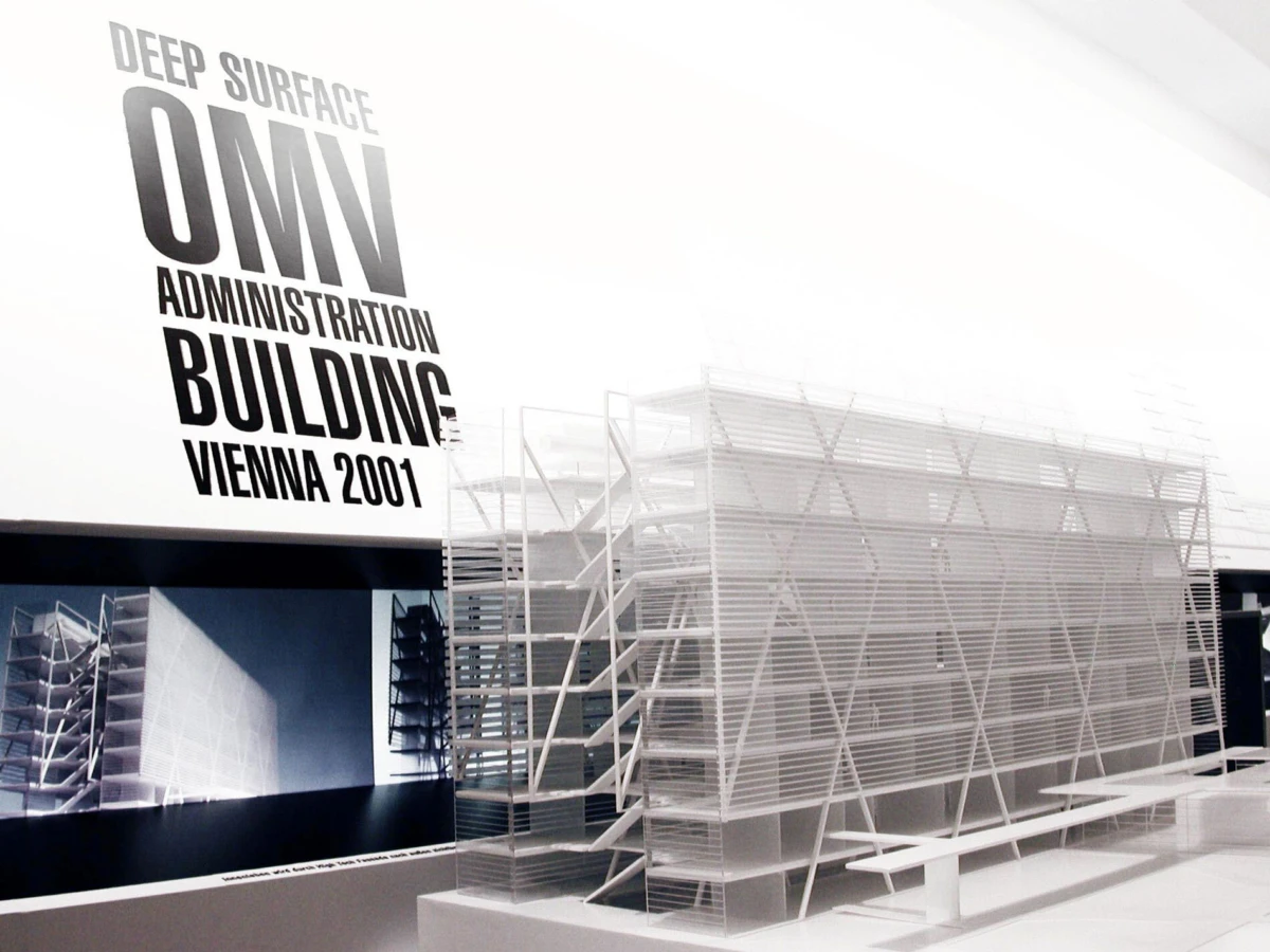 Scale architectural model of a building with lattice facade in an exhibition space; sign reads Deep Surface OMN Administration Building Vienna 2001.
