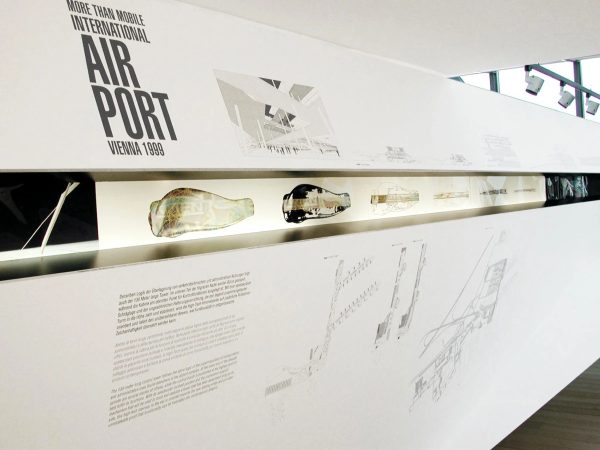 White museum display wall reading 'Air Port Vienna 1999' with airport schematics and cutaway models.