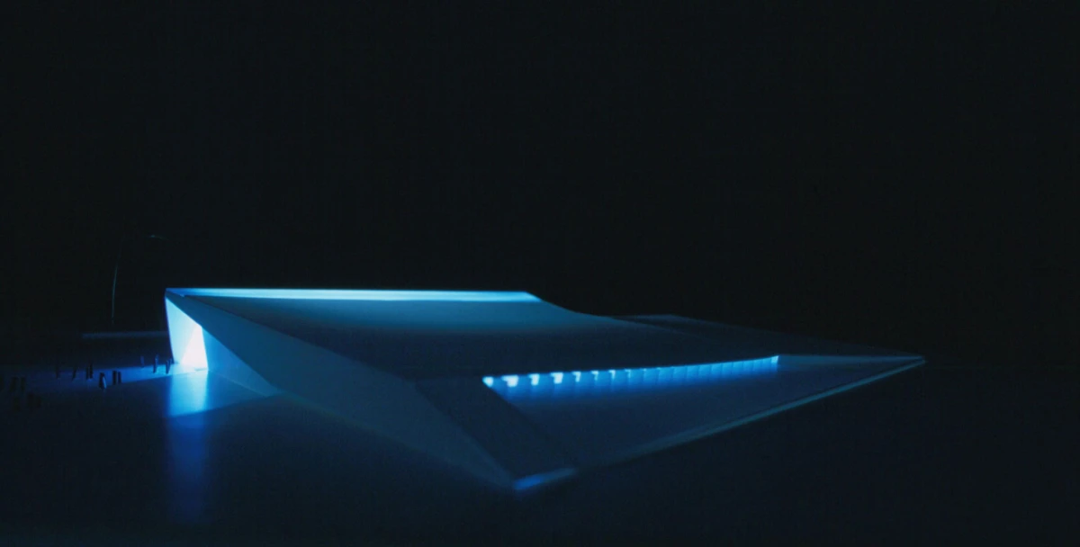 Futuristic angular pavilion glowing with blue lights at night.