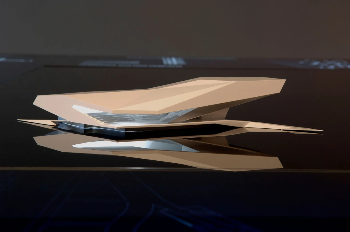 Angular beige origami-inspired sculpture resting on a glossy black surface, with reflection.