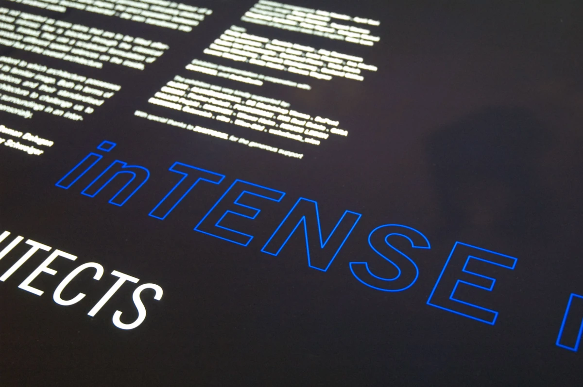 Diagonally oriented blue-outline "INTENSE" on a dark screen; small white text above.