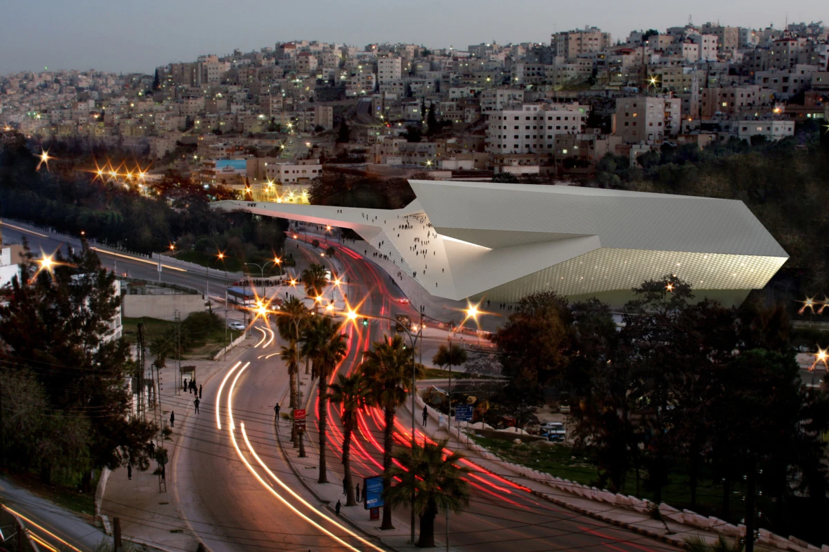 Angular, futuristic building with a slanted roof beside a busy curved road; pedestrians near its entrance in a hillside city at dusk.