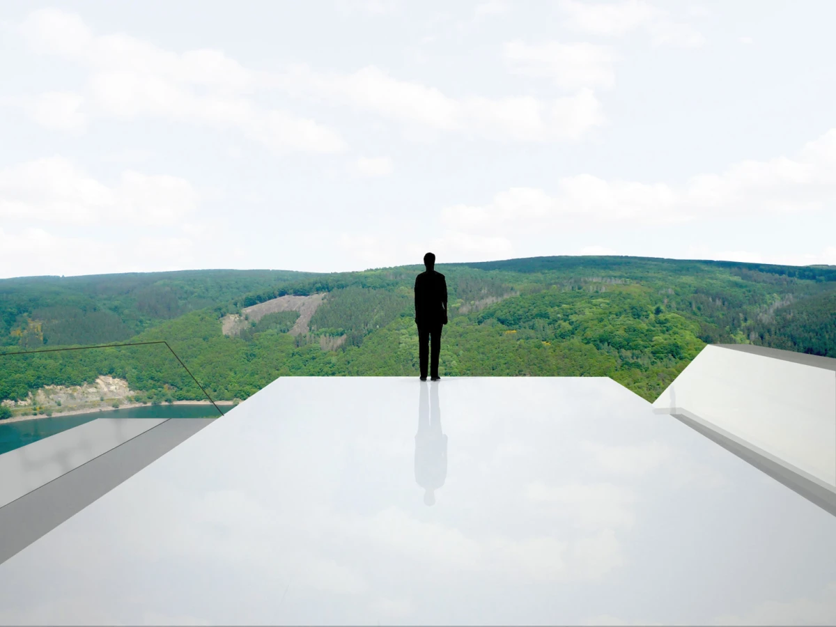 Silhouetted figure standing on a reflective glass platform, overlooking a forested valley beneath a cloudy sky.