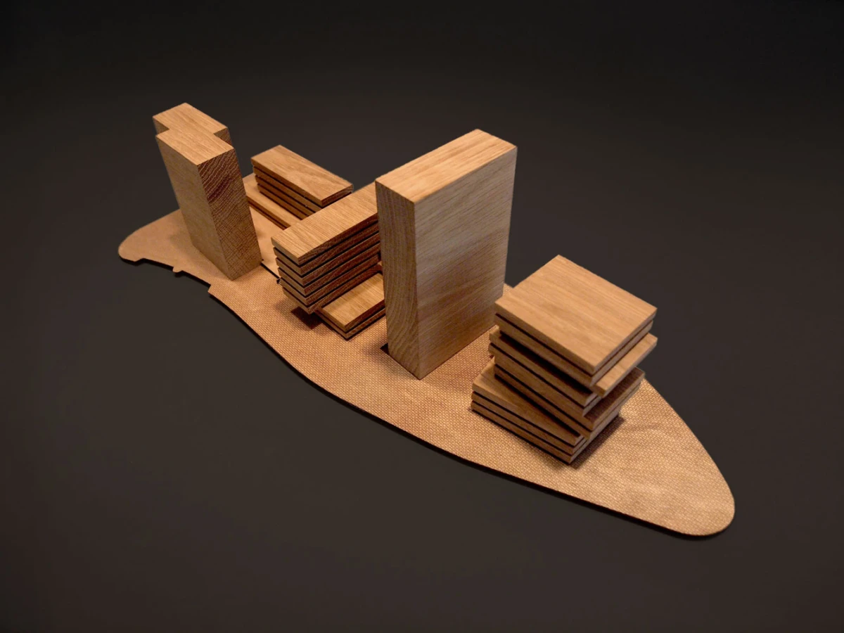 Wooden block city model on a curved wooden base, with tall and stacked rectangular prisms as buildings.