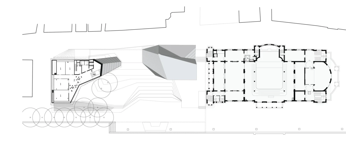 Architectural site plan: large rectangular building with central courtyard, left angled block, connected by a shaded passage; circular tree clusters foreground.