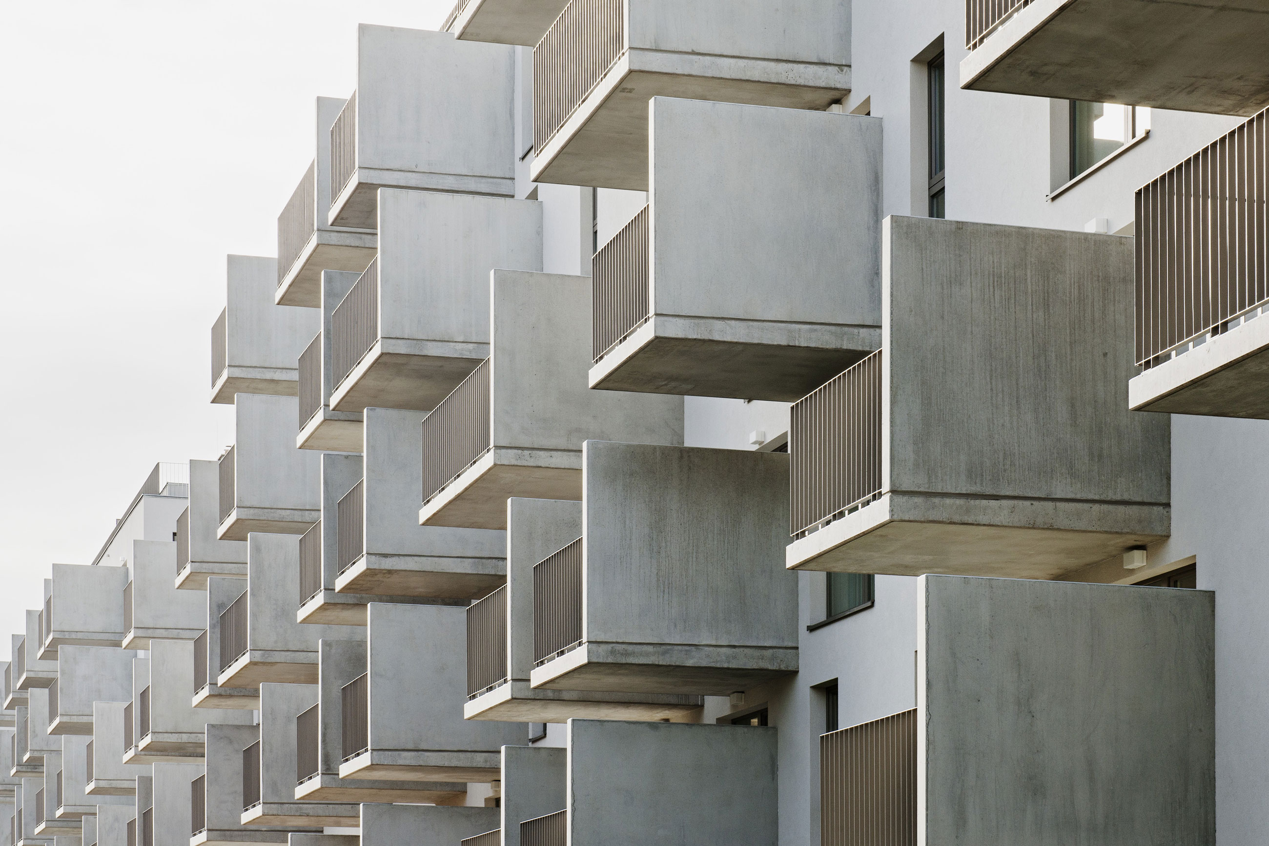 Rows of concrete balconies jut from a modern apartment building, creating a geometric, repetitive facade.