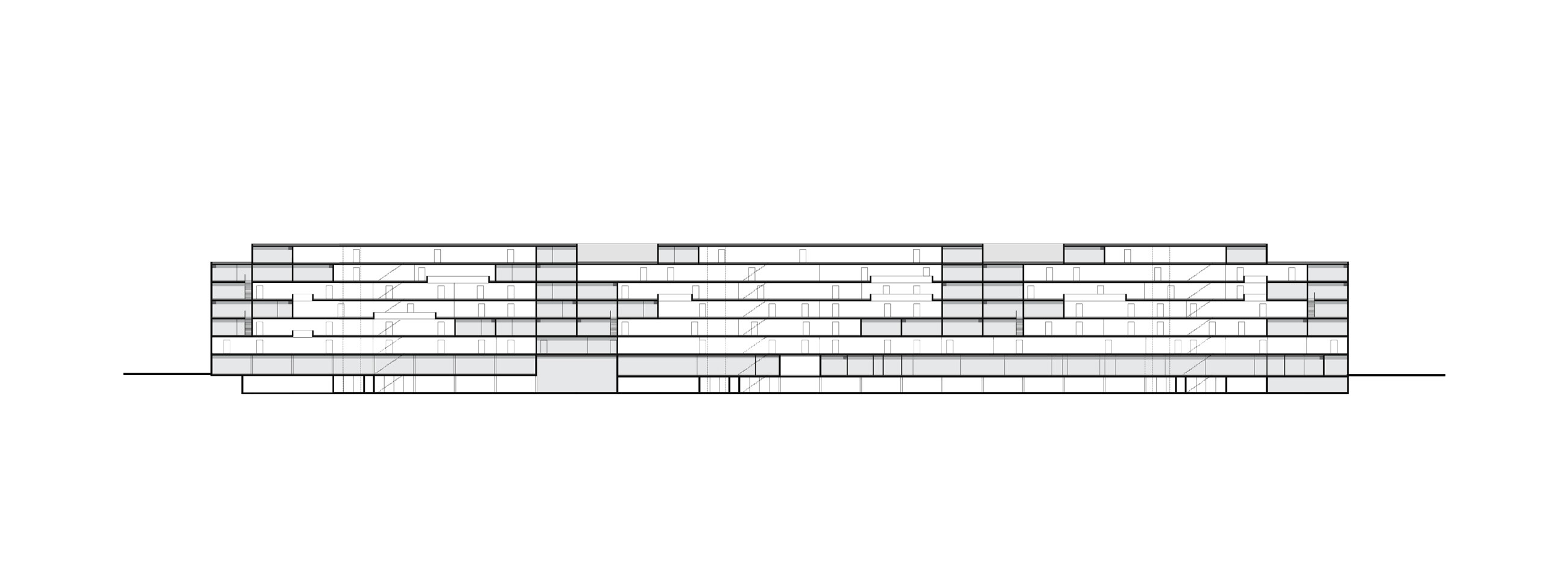 Long, low-rise modern building with stacked horizontal slabs and glass facade along a street.