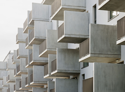 Rows of concrete balconies jut from a modern apartment building, creating a geometric, repetitive facade.