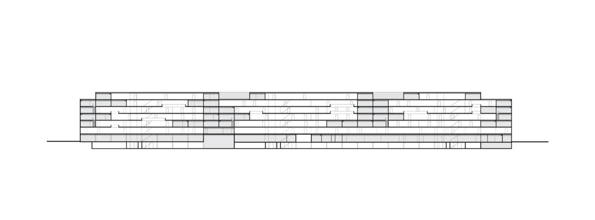 Long, low-rise modern building with stacked horizontal slabs and glass facade along a street.