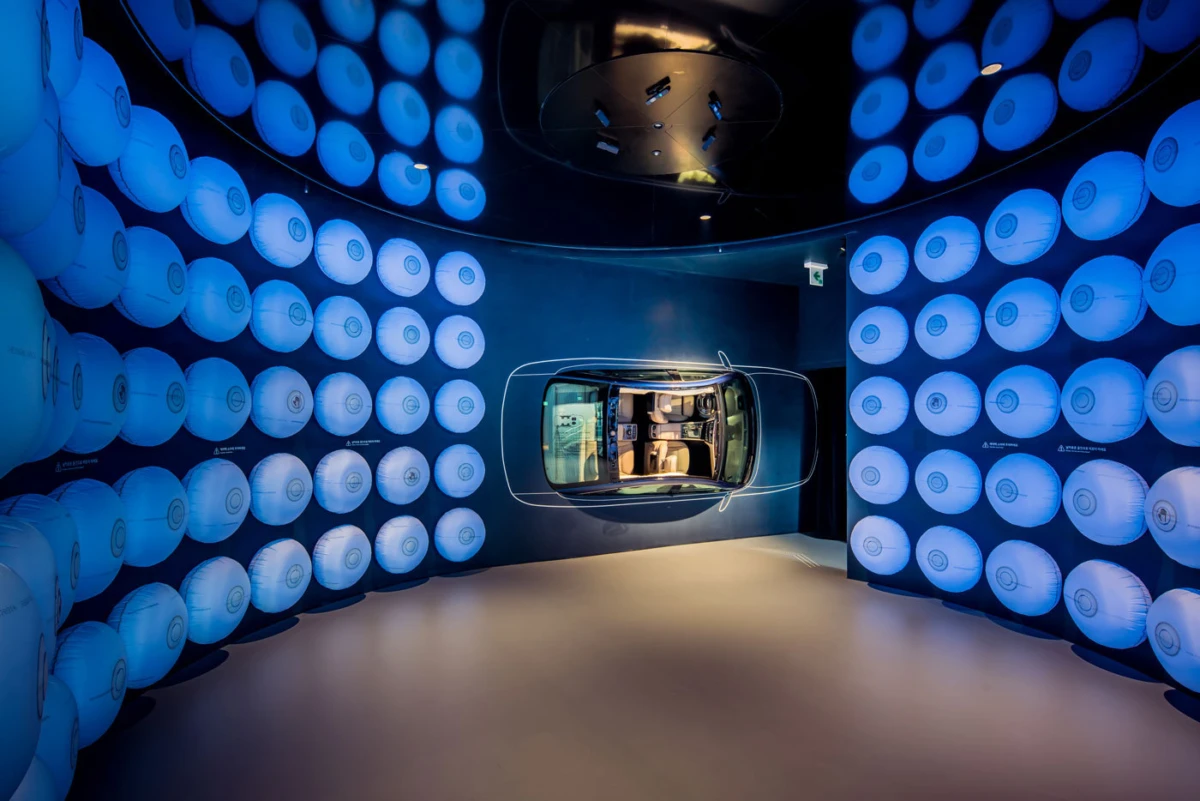 Car on display in a blue-lit exhibition chamber surrounded by circular wall panels.