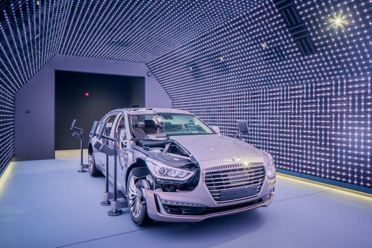 Silver sedan exhibiting front-end damage inside a futuristic LED-lit testing chamber.