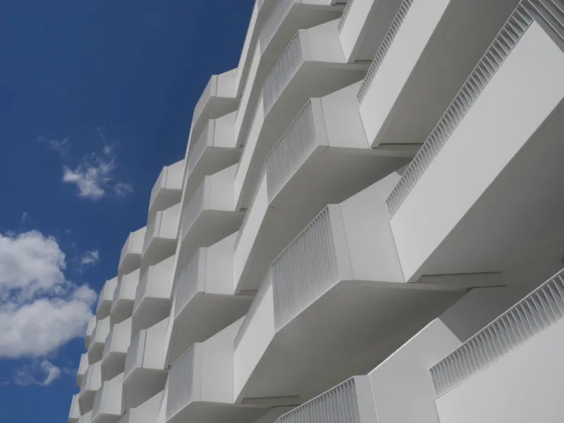 White apartment building with cantilevered balconies set against a blue sky