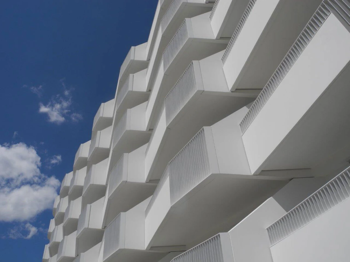 White apartment building with cantilevered balconies set against a blue sky