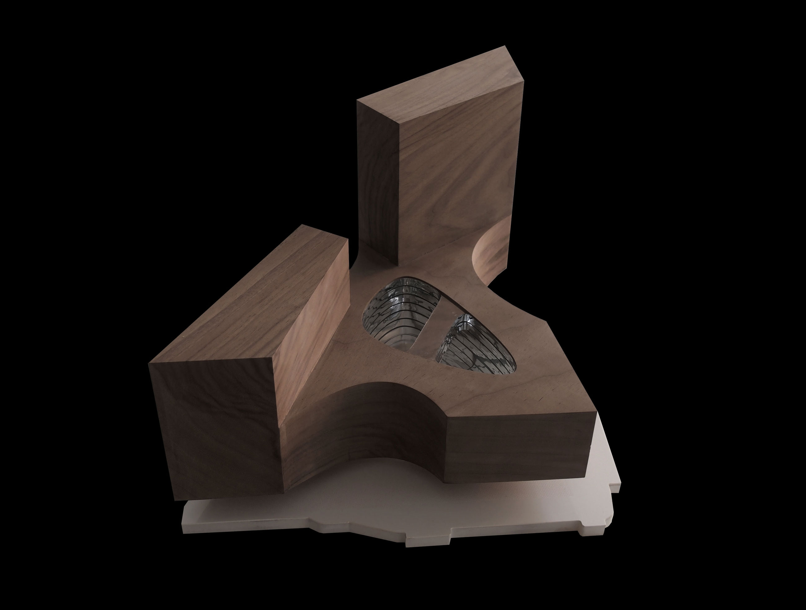 Wooden abstract sculpture with a curved notch and circular opening housing metal springs, on a white base against a black background.