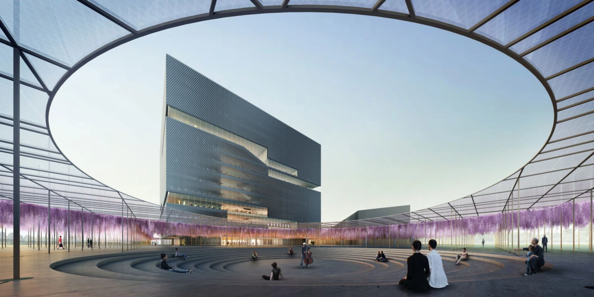 Circular outdoor amphitheater with concentric seating under a curved glass canopy; modern dark building in the background, purple flowering trees, people seated.