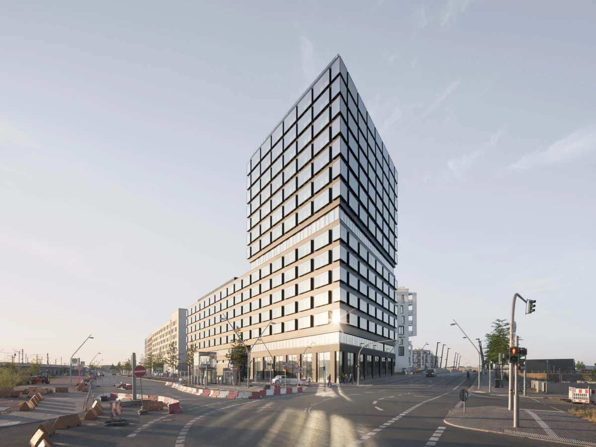 Modern glass high-rise with a stepped, angled facade rises above a street intersection, with construction barriers and traffic signals.