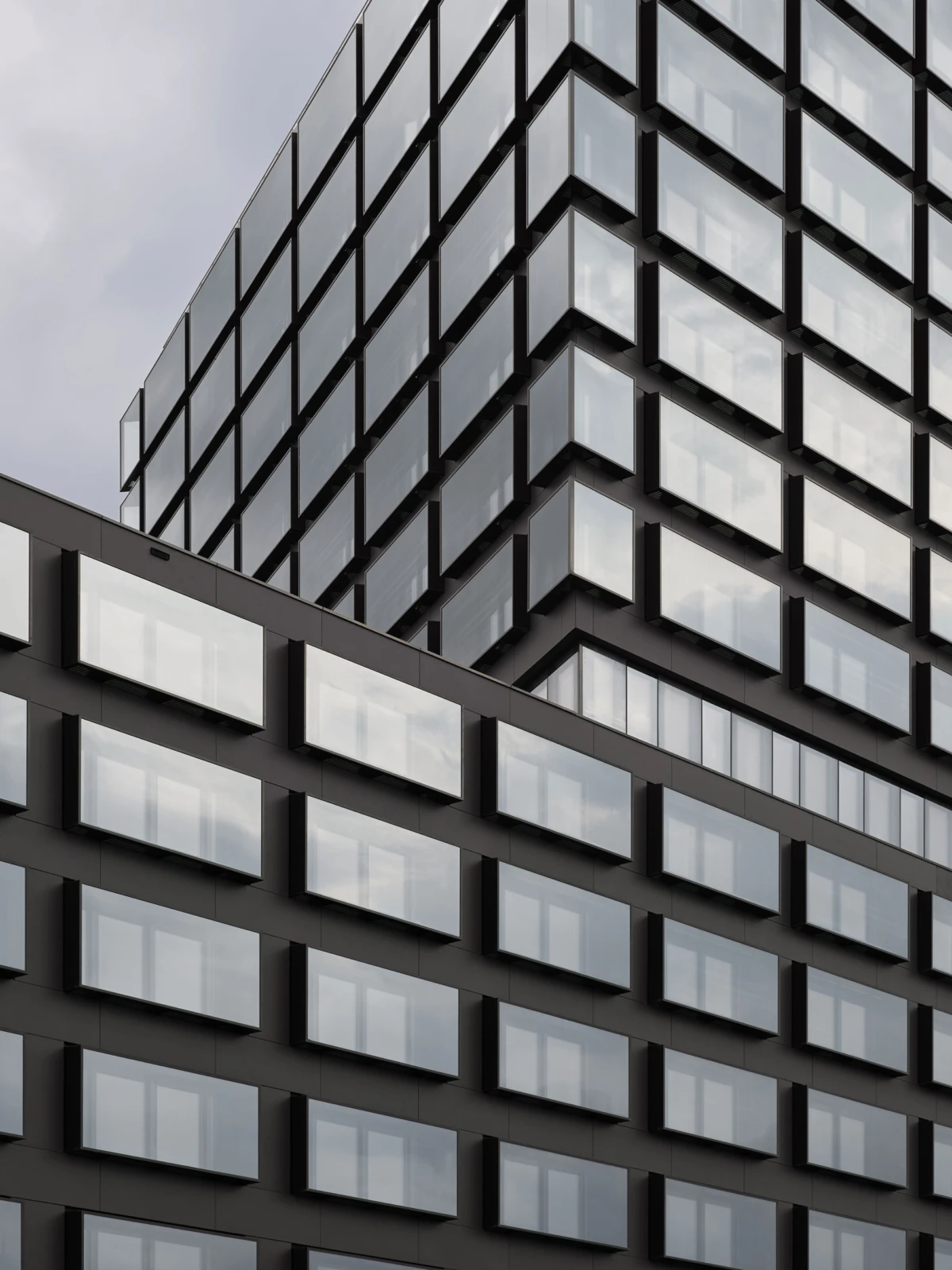 Glass-clad high-rise with a grid of rectangular windows, viewed from an angled perspective.