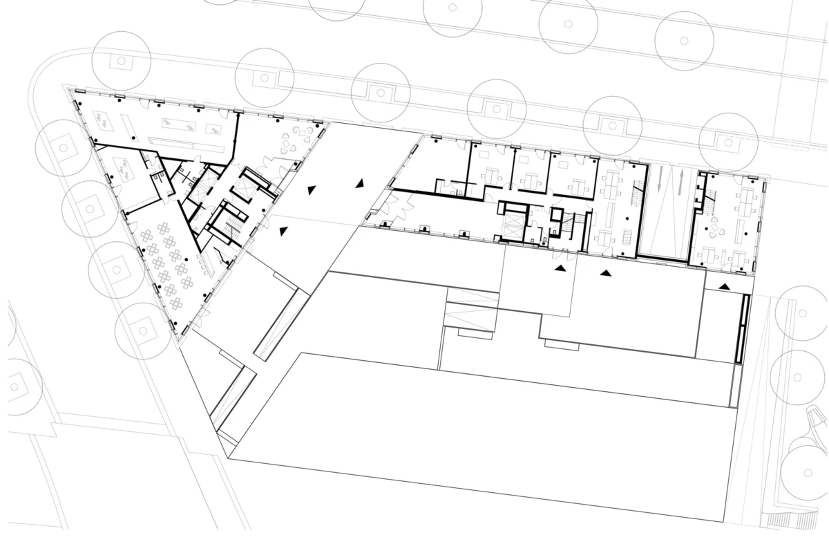 Architectural floor plan of a building with a triangular wing, showing offices, conference rooms, corridors, and surrounding site with trees.