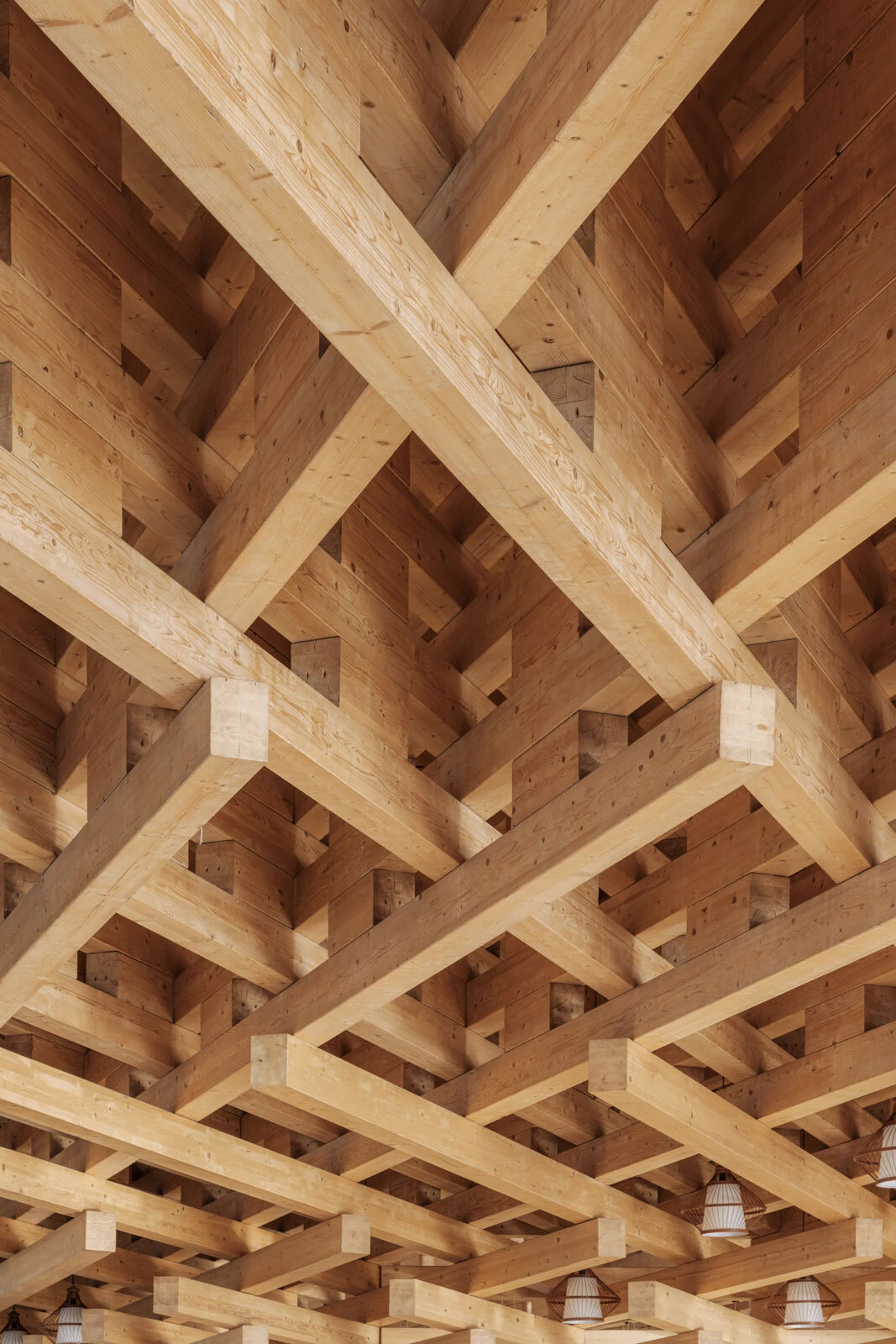 Crisscrossing wooden beams form a lattice ceiling with visible hanging pendant lights.