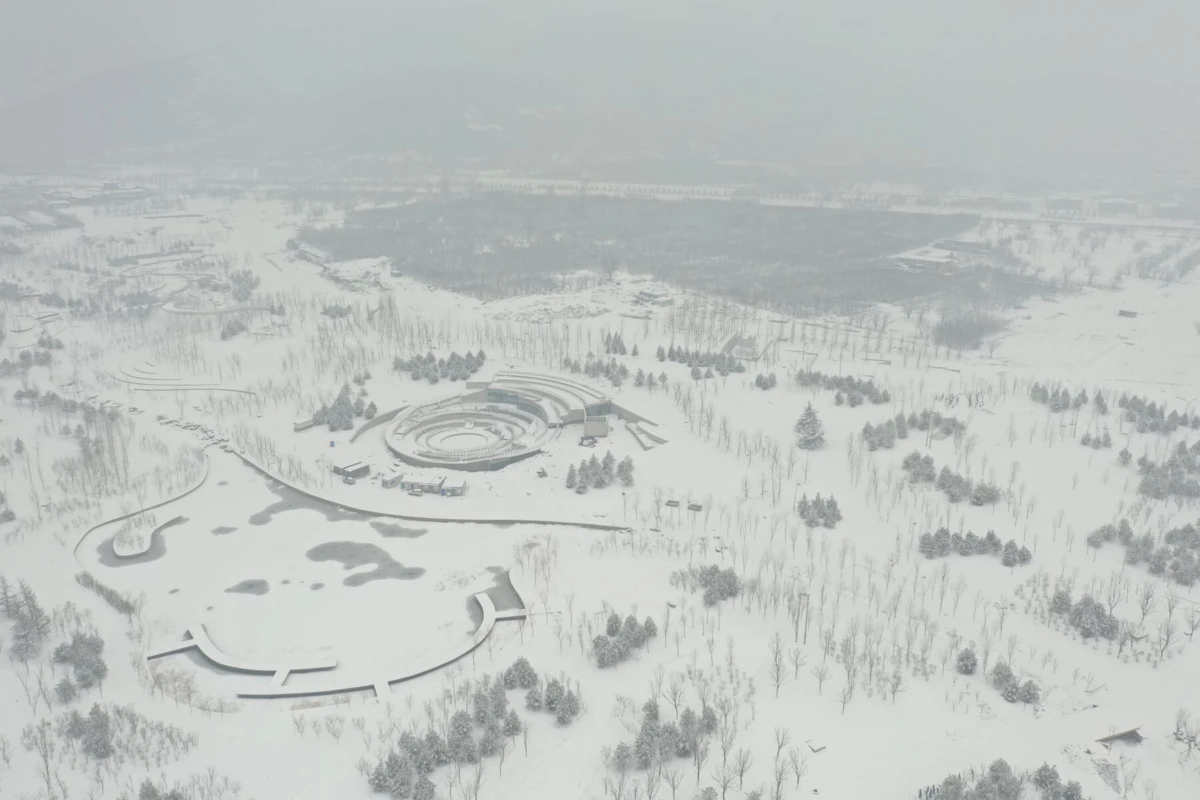 Aerial view of a snow-covered park with circular, ring-shaped structures and sparse trees.
