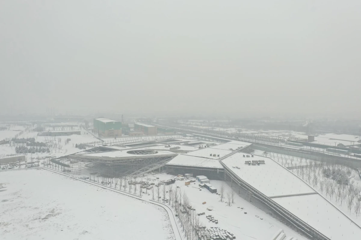 Aerial view of a snow-covered modern railway station complex featuring a circular rotunda and angular wings.