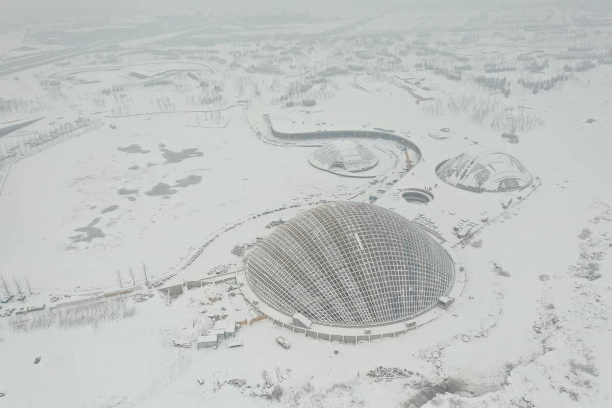 Aerial view of a snow-covered landscape featuring a large glass geodesic dome and several smaller domes.