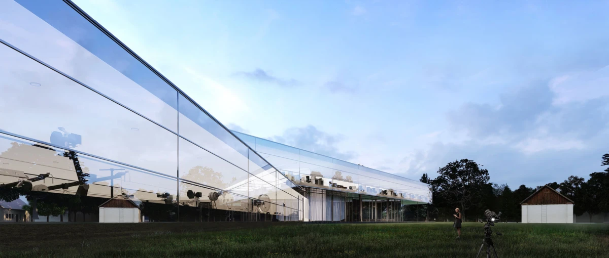 Glass-fronted modern building with reflective panels on a grassy field; a person films with a tripod-mounted camera.