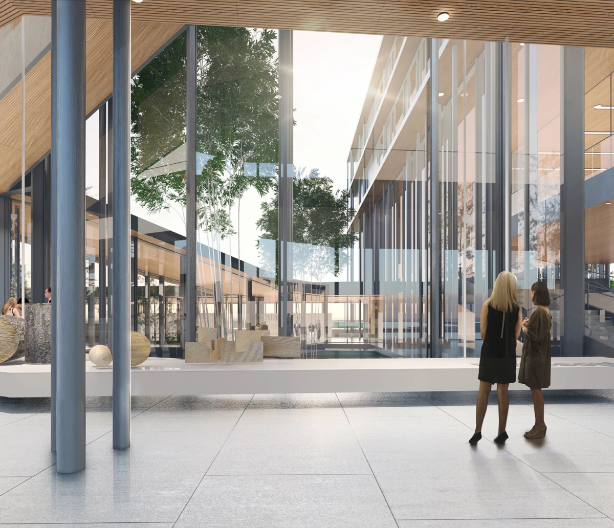 Two people conversing in a modern glass-walled atrium; trees visible through the glass.