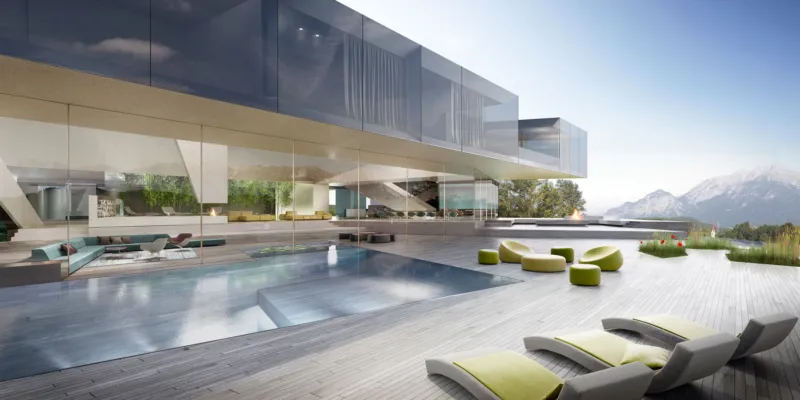 Modern glass-walled villa with an outdoor pool and lounge seating on a wooden deck, with mountains in the background.