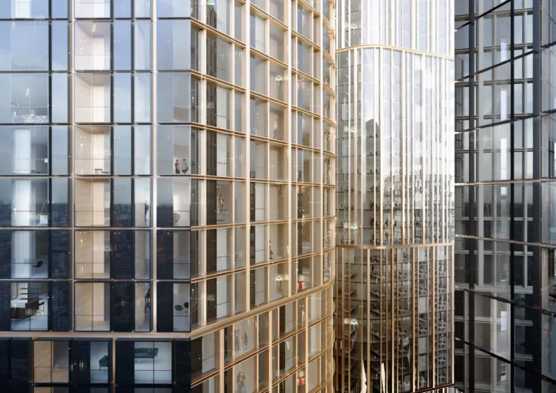 Glass-clad skyscrapers with curved golden frames; interior offices visible through windows in a dense urban skyline.