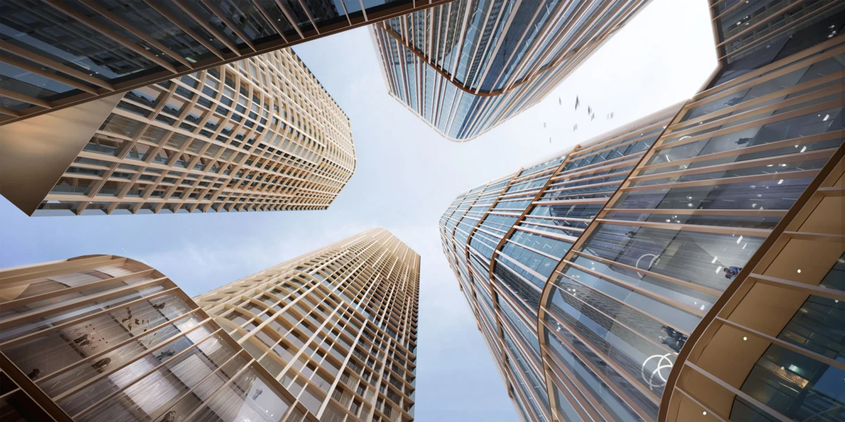 Low-angle view of tall glass skyscrapers encircling the blue sky, seen from the ground looking upward.