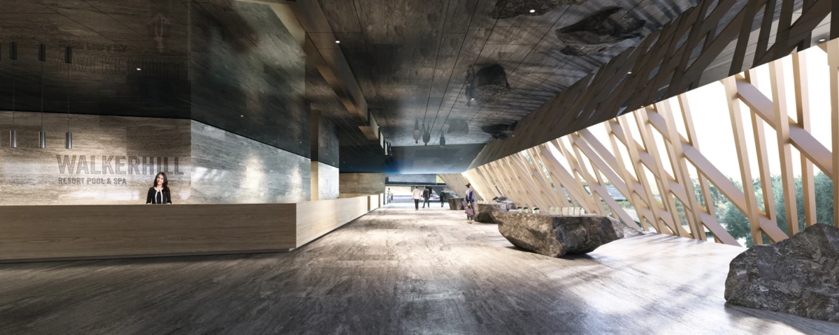 Modern hotel lobby with wooden ceiling, angled lattice windows, a receptionist at a long desk, and stone benches as people walk through.